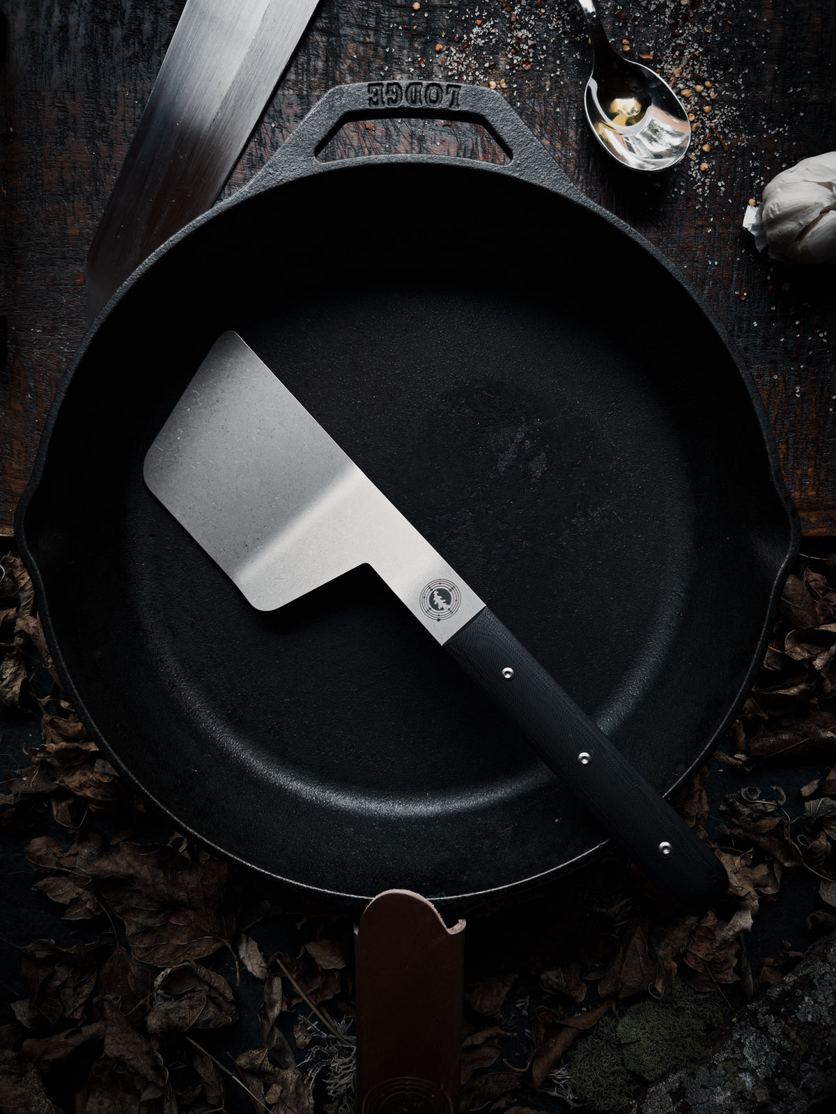 full size spatula with black handle sitting in a cast iron pan