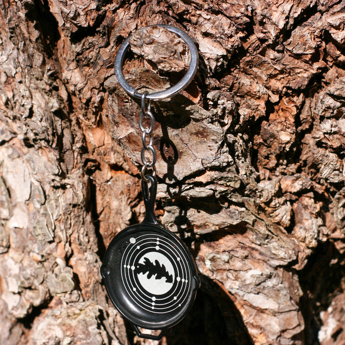 skillet keychain hanging on tree bark