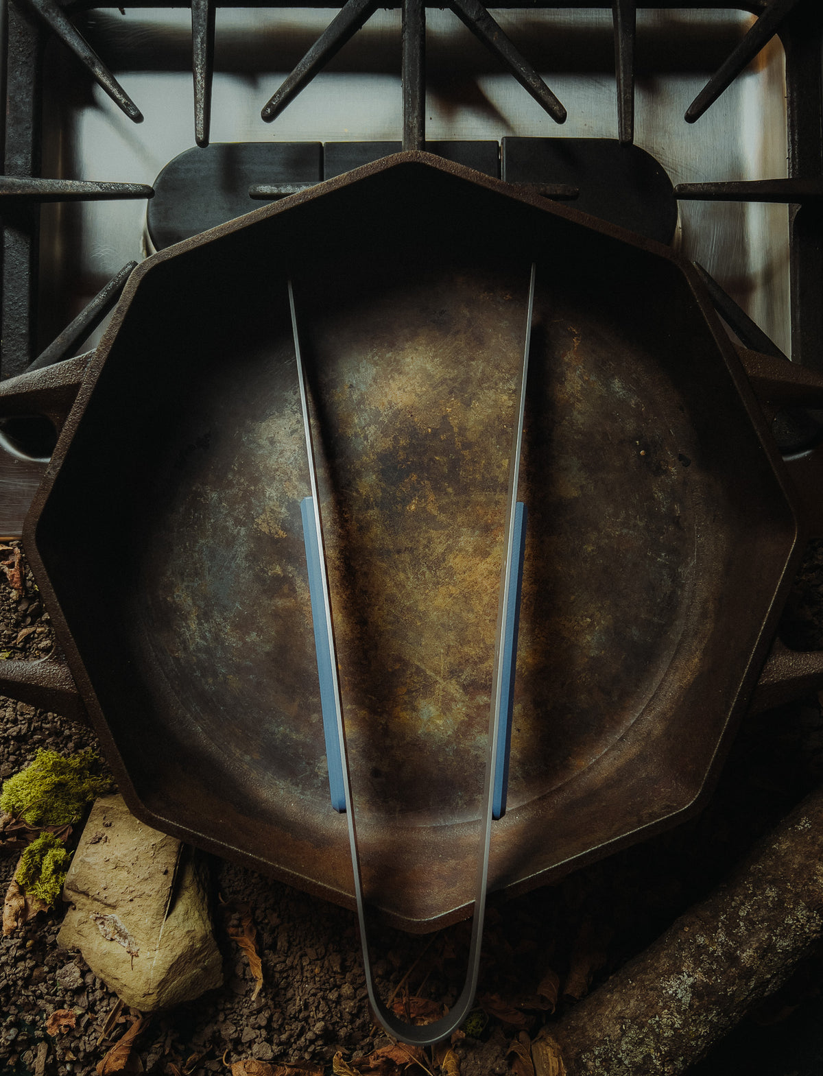 a blue handled titanium tong sitting in a skillet